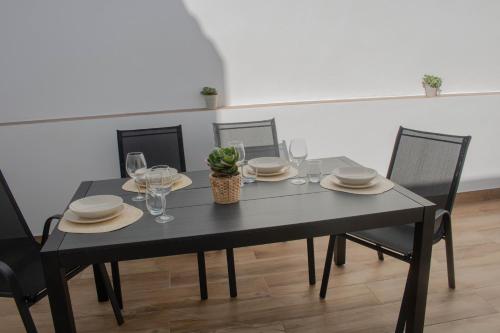una mesa de comedor negra con sillas, vasos y una planta en Casa Da´Mar, en Marbella