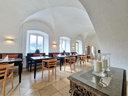 ein Esszimmer mit Tischen, Stühlen und Fenstern in der Unterkunft Schloß Ort in Passau