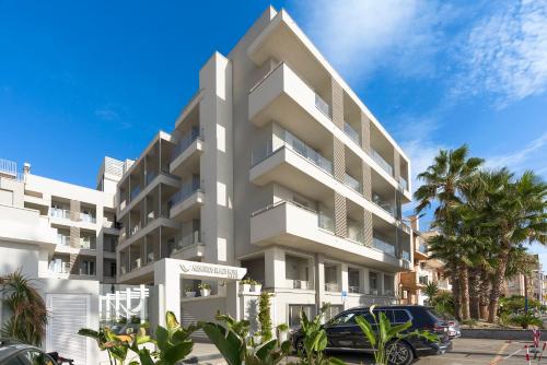 a white apartment building with a car parked in front at Albatros Beach Hotel in Letojanni