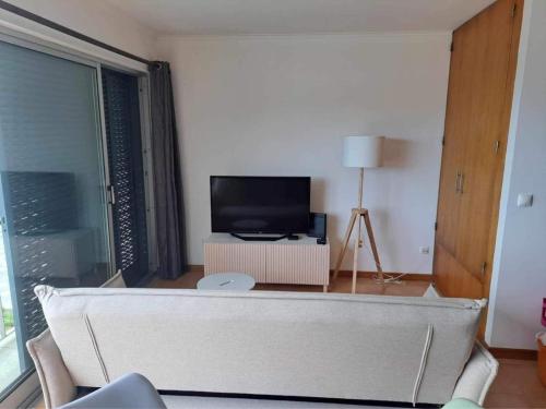 a living room with a couch and a television at Estúdio Frente Mar in Horta