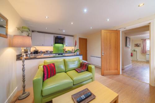 a living room with a green couch and a table at 1 Peggies Barn in Maulds Meaburn