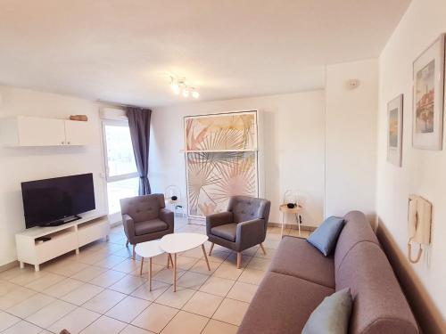un salon avec un canapé et deux chaises et une télévision dans l'établissement Studio à la mer avec piscine, à Sète