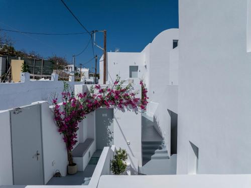 a white building with stairs and a tree with pink flowers at Cycladic Suites & Spa in Fira