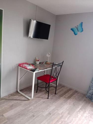 a desk with a chair and a tv on a wall at maison ancienne in Louviers