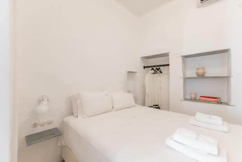 a white bedroom with a white bed and a mirror at aníko suites White Alley in Mýkonos City