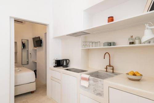 a kitchen with white cabinets and a sink at aníko suites White Alley in Mýkonos City