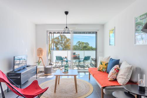 a living room with a couch and a table at Appartement Vue Mer 50m plage des Salins Piscine 2 parkings Terrasse in Hyères