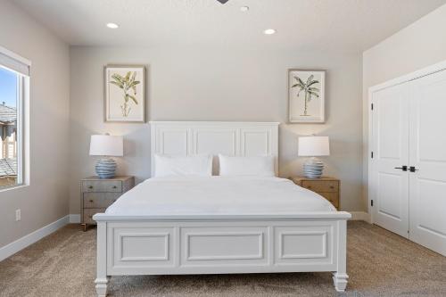a white bedroom with a white bed and two lamps at Zion's Paradise townhouse in Hurricane