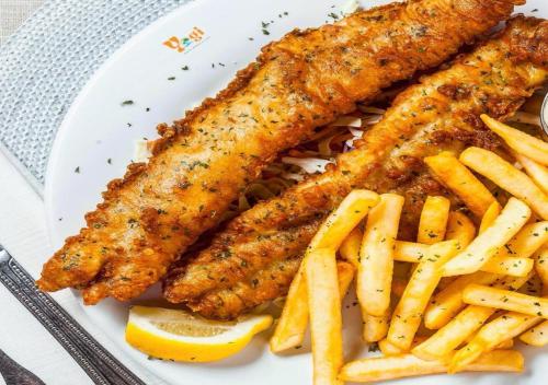 a plate of food with fish sticks and french fries at YogiTree Beach Resort & Cafe - 100m from Morjim Beach in Morjim
