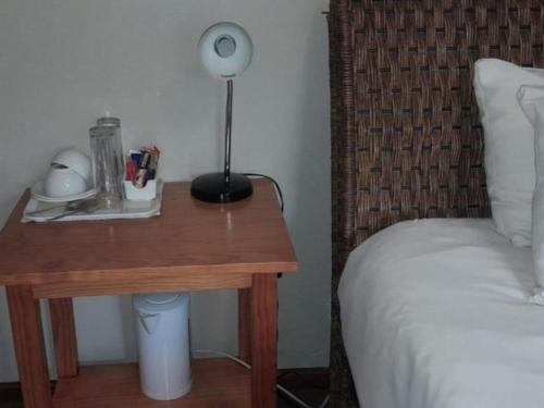 a table with a lamp on it next to a bed at Port St Johns River Lodge in Port St Johns