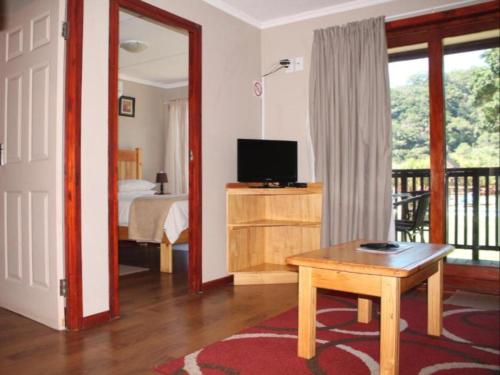 a room with a bedroom with a bed and a table at Port St Johns River Lodge in Port St Johns