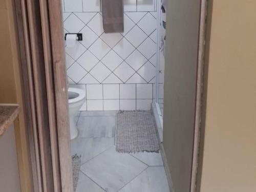 a bathroom with a toilet and a white tile floor at Port St Johns River Lodge in Port St Johns