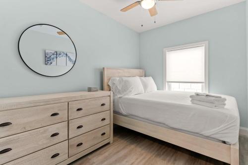 a bedroom with a bed with a dresser and a mirror at Fully Renovated - Walk to Beach - The Americana in Hampton