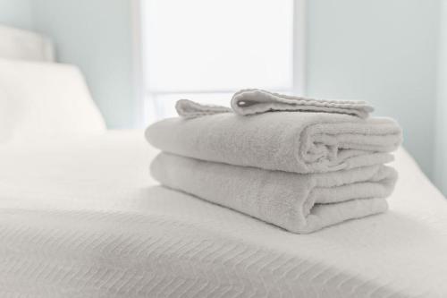 a stack of towels sitting on top of a bed at Fully Renovated - Walk to Beach - The Americana in Hampton
