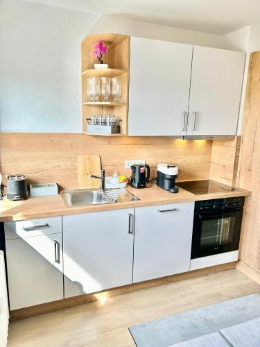 a kitchen with white cabinets and a sink at Diamond Apartments: Residenz Dreiländereck nahe Flughafen in Herten
