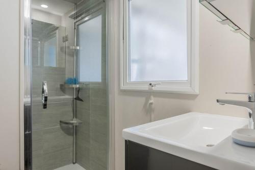 y baño blanco con lavabo y ducha. en Mobil home vacances en Puget-sur Argens