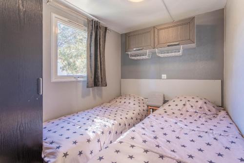 1 dormitorio con 2 camas y ventana en Mobil home vacances en Puget-sur Argens