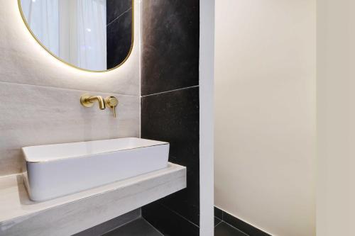 a bathroom with a white sink and a mirror at Exceptional studio Place des Vosges Marais in Paris