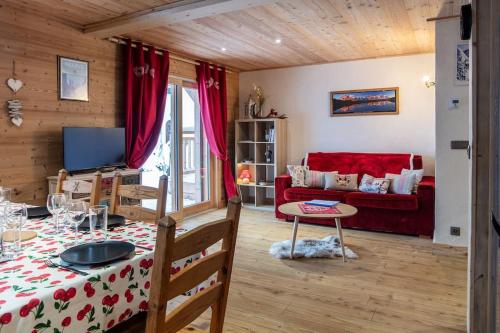 un salon avec une table et un canapé rouge dans l'établissement Charmant appartement dans chalet, coeur de Megève, à Megève