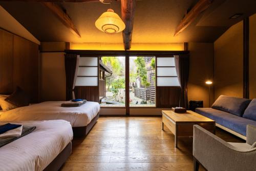 a room with two beds and a couch and a window at PAYSAGE MORIGUCHI in Mima