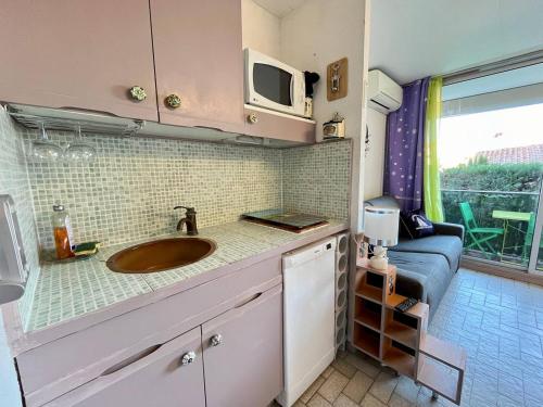 uma pequena cozinha com um lavatório e um micro-ondas em Studio cabine avec piscine au Grau du Roi em Le Grau-du-Roi