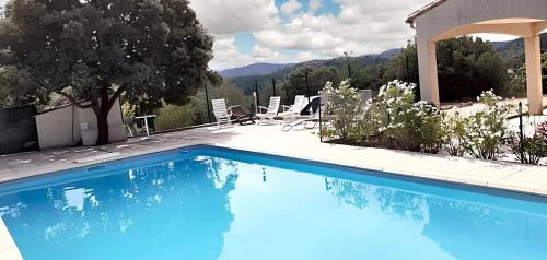 une piscine bleue avec des chaises et une maison dans l'établissement Spacieuse villa à Saint-Jean-du-Pin avec piscine privée, à Saint Jean du Pin