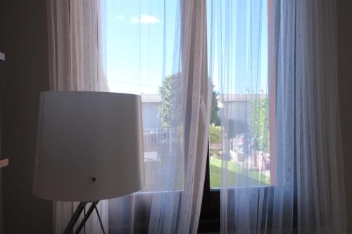 チェルノッビオにあるCà di Striiの白いカーテンと前にランプが付いた窓