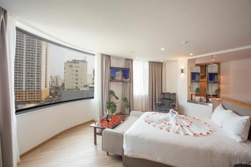ダナンにあるPĀMA Boutique Hotel & Bistroのベッドと大きな窓が備わるホテルルームです。
