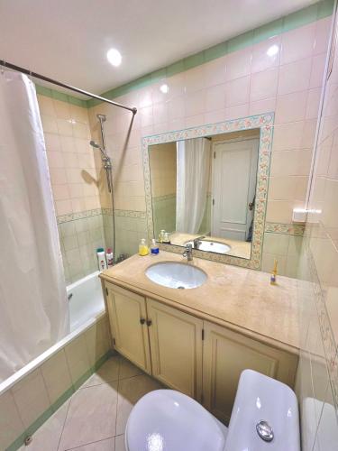 a bathroom with a sink and a mirror and a tub at Mike Beach House in Costa da Caparica