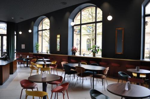 a restaurant with tables and chairs and windows at La Brasserie Hostel in Metz