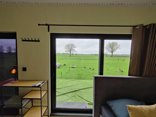 een woonkamer met uitzicht op een veld door een glazen schuifdeur bij Tiny House Betuwe in Tricht