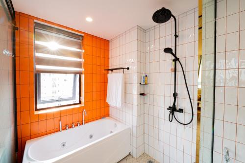 an orange bathroom with a tub and a window at PĀMA Boutique Hotel & Bistro in Da Nang