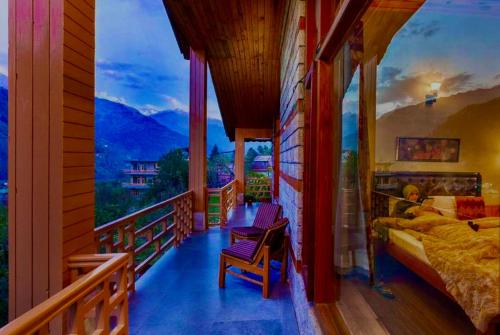 1 dormitorio con balcón con cama y vistas en Nature Valley Resort Manali 2 Bedrooms luxury Cottages, en Manali