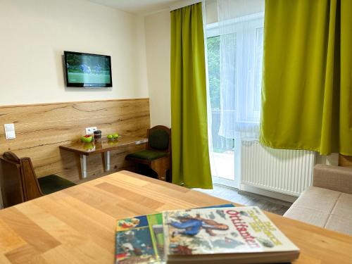 a living room with a table and a green curtain at Hotel Waldberg in Stolberg