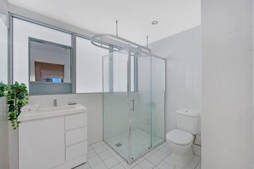 een badkamer met een douche, een toilet en een wastafel bij Sky View 2B1B@burwood in Sydney