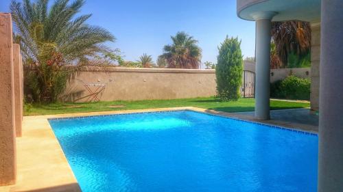 a large blue swimming pool in a yard at Paradise Villa - King Mariout in King Mariout