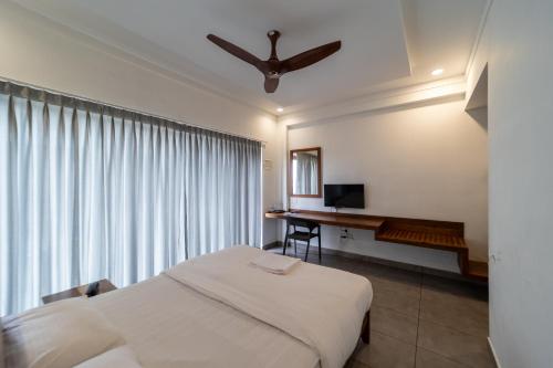 a bedroom with a bed and a desk and a ceiling fan at WINTEL WILD in Vālpārai