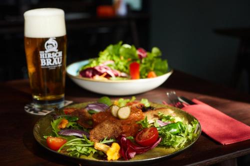 a plate of food with a salad and a glass of beer at Hotel Zum Goldenen Hirsch in Sonthofen