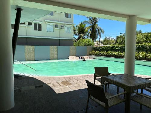 einen Pool mit einem Tisch und Stühlen sowie ein Gebäude in der Unterkunft One Spatial Condominium, 2-Bedroom Unit #2920 in Iloilo City