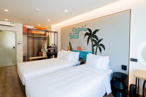 two beds in a hotel room with white sheets at PĀMA Boutique Hotel & Bistro in Da Nang