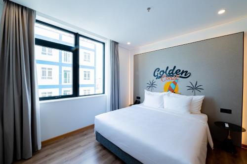a bedroom with a white bed and a large window at PĀMA Boutique Hotel & Bistro in Da Nang