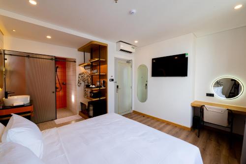 a bedroom with a large white bed and a bathroom at PĀMA Boutique Hotel & Bistro in Da Nang