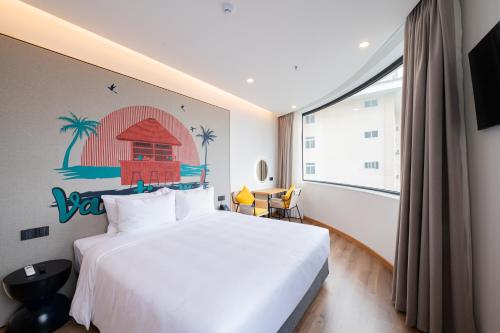 a bedroom with a white bed and a large window at PĀMA Boutique Hotel & Bistro in Da Nang