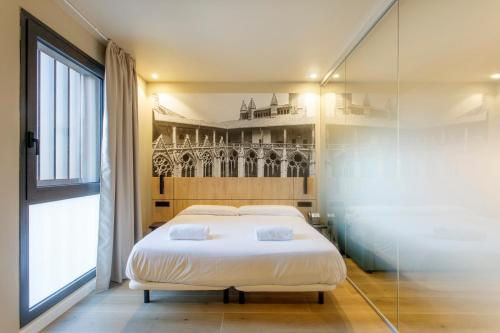 a bedroom with a white bed and a large window at Hotel Landaben in Pamplona