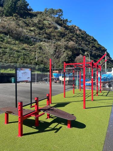 a playground with red poles and benches on the grass at Del Valle 1 in Cudillero