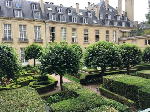 un jardin en face d'un grand bâtiment avec des arbres et des buissons dans l'établissement Magnifique studio coeur Marais, à Paris