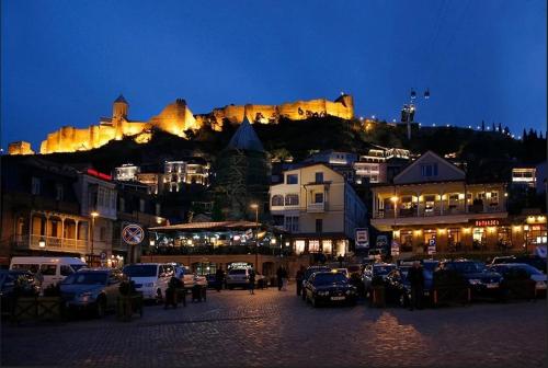 uma cidade com um castelo no topo de uma montanha à noite em Love is... em Tbilisi