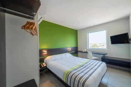 - une chambre avec un lit et un mur vert dans l'établissement City Express Junior by Marriott Toluca Zona Industrial, à Toluca