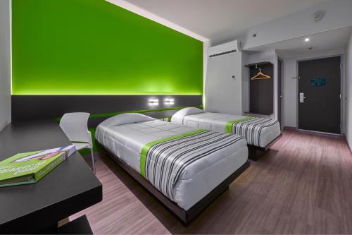 two beds in a room with a green wall at City Express Junior by Marriott Toluca Zona Industrial in Toluca