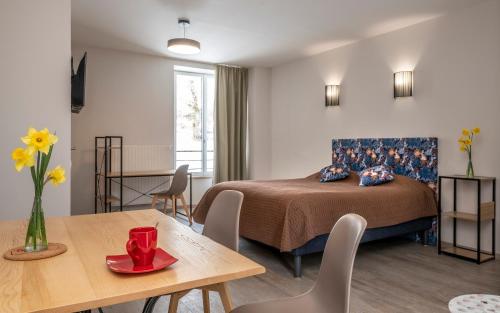 a hotel room with a bed and a table and a dining room at Logis Hôtel Restaurant de la Poste et La Grange Détente, espace bien-être in Châteauneuf-de-Randon